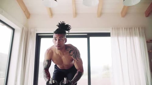 Shirtless Man Exercising with Dumbbells at Home