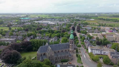 A stunning aerial view of a European town with a historic church and green fields stretching