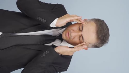 Man in Suit Rubbing Temples in Distress