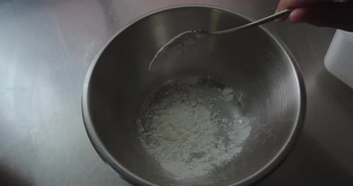 Wunderschöne Zeitlupenaufnahme eines Kochs, der Mehl mit einem kleinen Löffel in eine Schüssel gibt, um das Pommes zu kochen