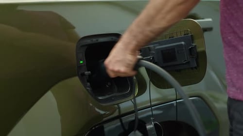 Close Up of Driver Disconnecting EV Vehicle From Charging Dock