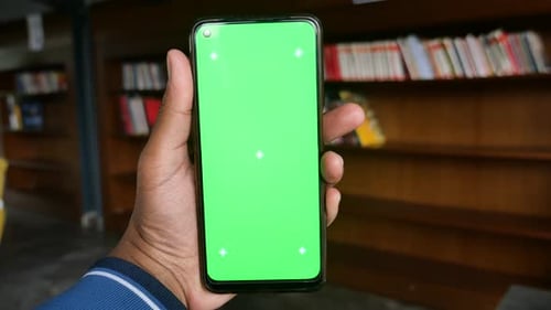 Man with Green Screen Phone in Library