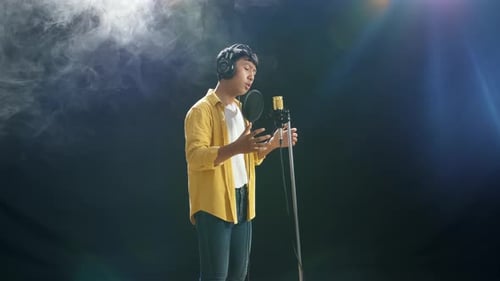 Young Adult Singing Into Microphone In Studio
