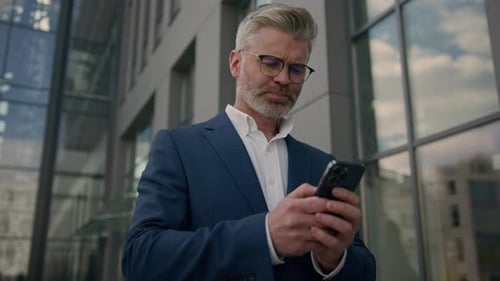 Man in Suit Using Phone Outside Office Building