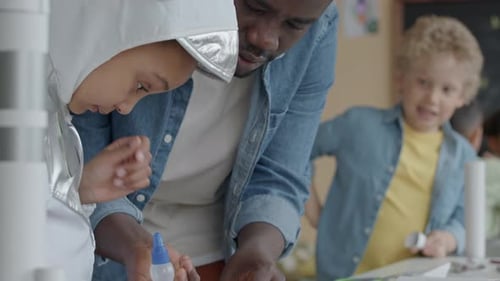 Teacher Helping Child with Spacesuit Craft in Classroom
