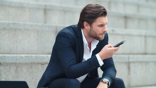 Confident Business Man Recording Audio Message on Smartphone at Street. Serious Employee