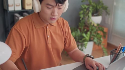 Developer in Headphones Testing App on Laptop