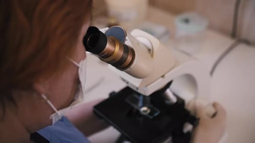 Doctor in Hospital Laboratory Looking Through Microscope