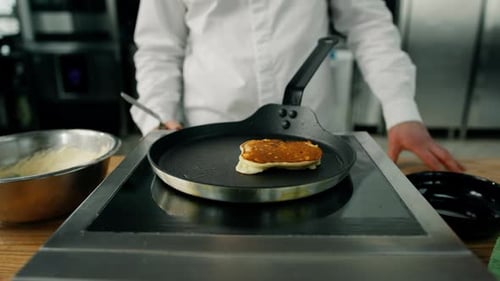 Chef Preparing Pancakes in a Pan on a Stove