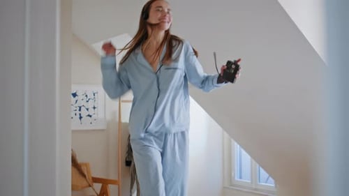 Young Woman Joyfully Jumping on Bed with Headphones