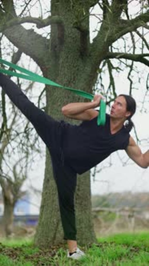 Muscular Man Stretches Outdoors with Resistance Band