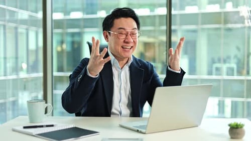 Korean Businessman Celebrating Success on Laptop in Modern Office