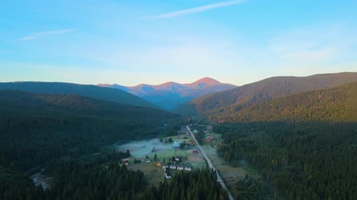 Aerial View of Foggy Evening Over Small Mountain Village Homes Between High Peaks with Dark Pine