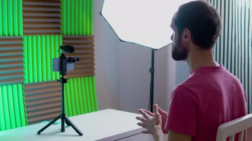 A Young Blogger Records a Video with Himself on His Smartphone in His Room Studio