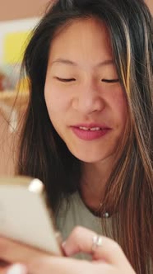 Close-up, smiling young woman sitting on the sofa writes SMS with a mobile phone