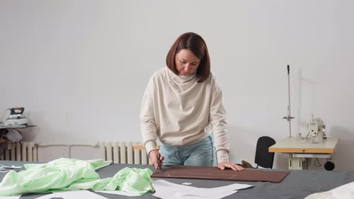 Seamstress Cutting Fabric Design on Work Table in Sewing Studio