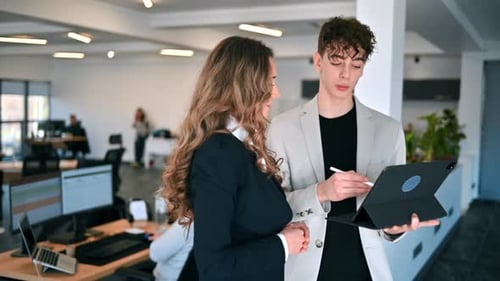 Business session in an office. Woman and a young man discussing business affairs, tablet. Slow motio