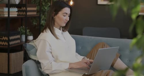 Woman Typing on Laptop on Couch Indoors