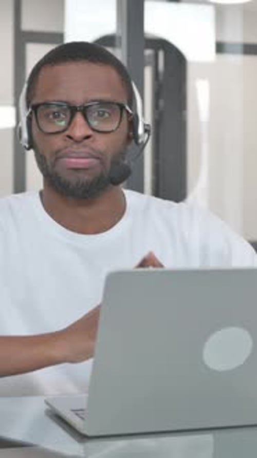 Man Using Laptop with Headset in Office Setting
