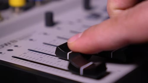 Musician moves key on mixing remote control with his hand to adjust sound,