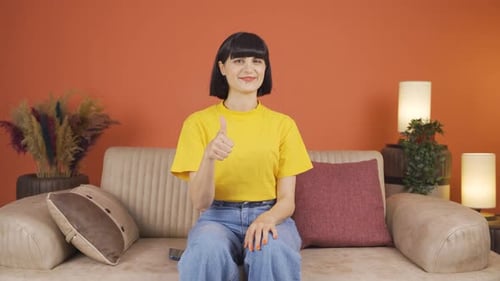 Woman Gives Thumbs Up While Sitting on Couch