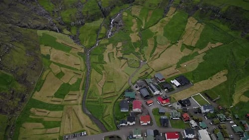 Drone capturant le village de Tjørnuvík, îles Féroé, avec des champs cultivés et un ruisseau