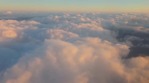 Flying over the clouds illuminated by sunlight