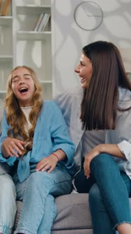 Mother and Children Laughing Together on Sofa Indoors