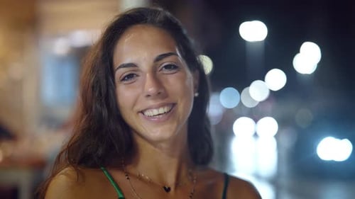 Uma jovem morena atraente está sorrindo para a câmera em um fundo de um movimentado centro da cidade com
