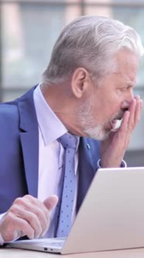 Senior Man Working on Laptop Coughs Repeatedly