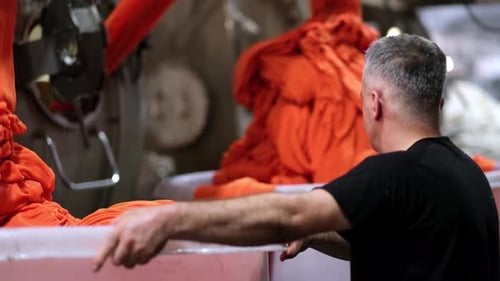 Factory Worker Inspecting Orange Textile Material Production