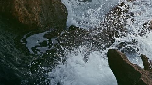 Ocean splashes foaming near hillside rocks at dusk by the sea nature landscape