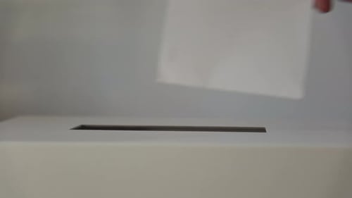 A Person Casts Her Ballot During Voting for Elections at a Polling Station