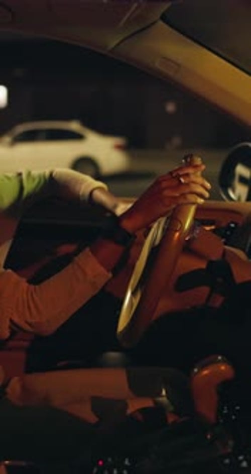 Hands Hold Car Steering Wheel at Night in City