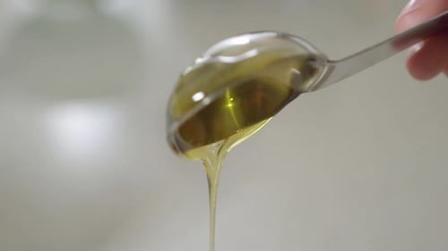 Close up of honey spoon as honey drips off it in slow motion