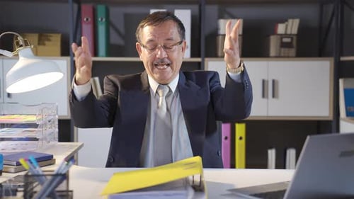 Man in Suit Gesturing with Folder at Desk