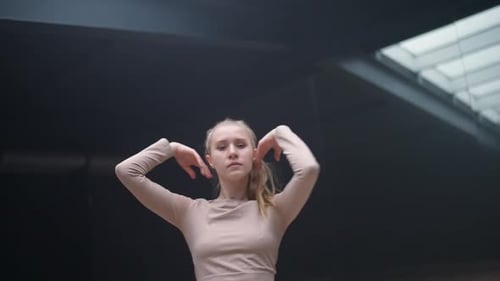 Expressive Blonde Woman Dances in a Dark Studio