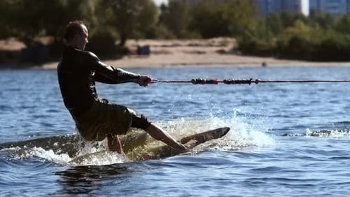 Wakesurfer Riding Surf Board on Waves in Sunny Day. Extreme Water Sport