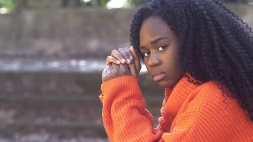 jovem africana absorta em uma atitude de oração olha para a câmera irritada