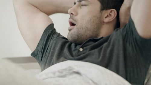 Man Waking Up and Stretching in Bed