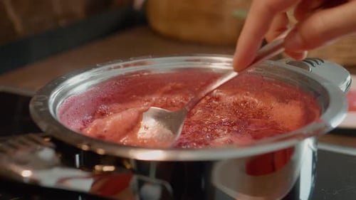 Red Jam Simmering in a Shiny Steel Pan