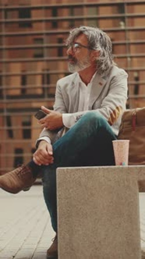 Mature businessman wearing gray jacket is using cell phone