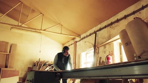 Mature carpenter carefully working with raw wood in his carpentry workshop