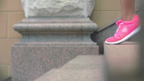 Woman's Legs Climbing Stone Stairway in Pink Sneakers