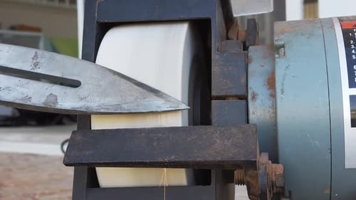 Slow motion video of a knife being sharpened on a knife grinder.