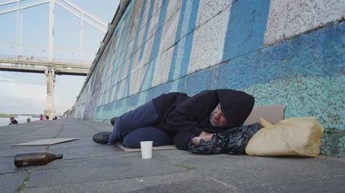 Obdachloser armer erwachsener Mann schläft auf dem Boden in der Stadt unter der Brücke Depressionsproblem Schmutzig