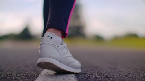 Läuferin in weißen Turnschuhen beginnt ihr Asphaltstraßentraining aus nächster Nähe