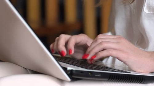 Junge Geschäftsfrau tippt auf Laptop-Tastatur und kommuniziert online in Innenräumen