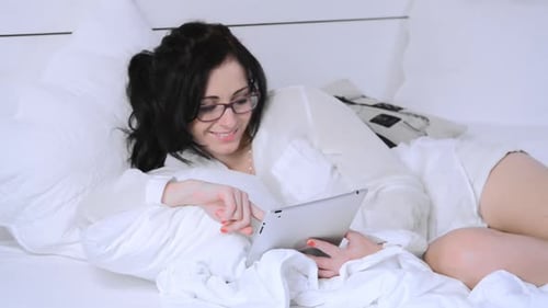 Woman Using Tablet Relaxing in White Bed