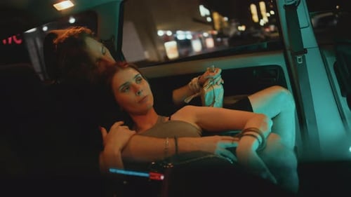 Young Couple Embracing in the Back of Car at Night